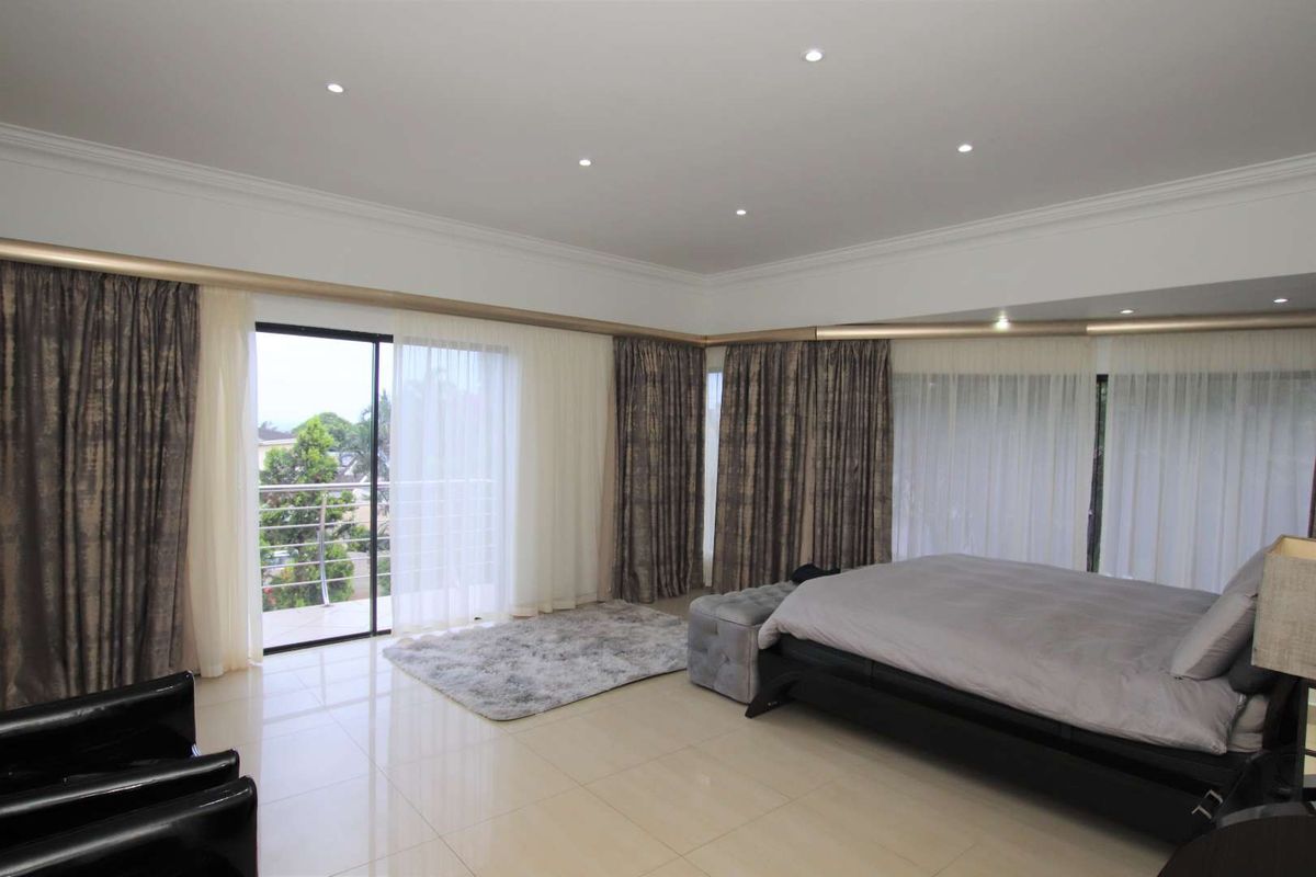Spacious bedroom featuring large sliding glass doors leading to a private balcony, polished tiled flooring, and recessed ceiling lighting.