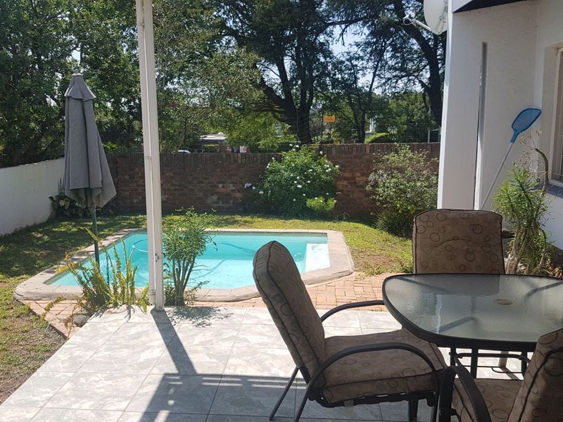 Outdoor patio area featuring a swimming pool, tiled flooring, and a brick boundary wall, offering a private space for relaxation and entertainment.