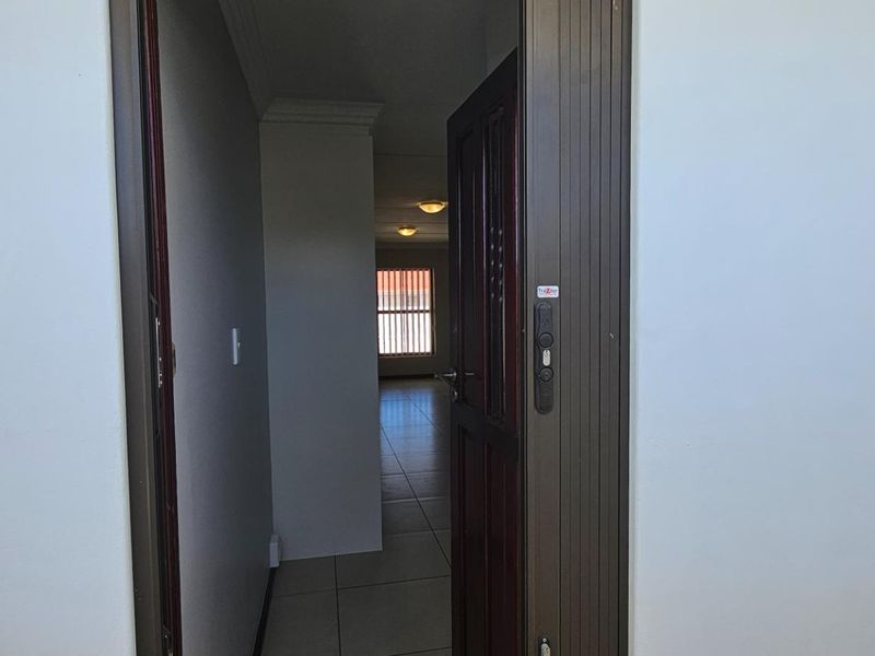 Entrance area featuring tiled flooring and a security gate, leading into an open-plan living space.