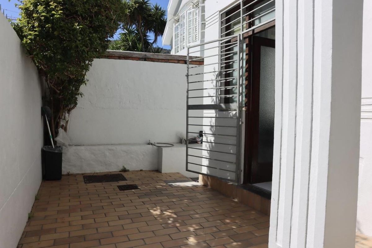A private rear courtyard area featuring brick paving, a secure metal gate, and a boundary wall with an external water tap.