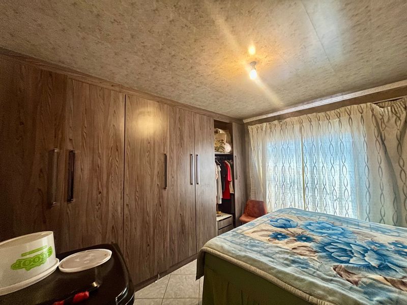 A bedroom featuring extensive built-in wooden cupboards and tiled flooring, providing ample storage space.