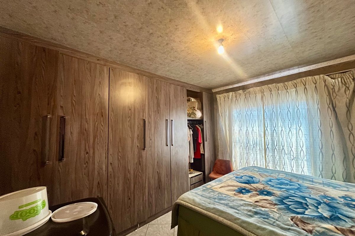 A bedroom featuring extensive built-in wooden cupboards and tiled flooring, providing ample storage space.