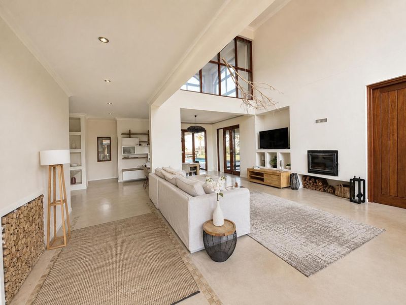 Spacious open-plan living area featuring high vaulted ceilings, polished concrete floors, a built-in fireplace, and integrated shelving with abundant natural light.