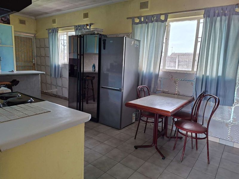 A dated kitchen featuring tiled flooring, tiled splashbacks, and built-in cabinetry, offering a functional layout with potential for modern renovation.