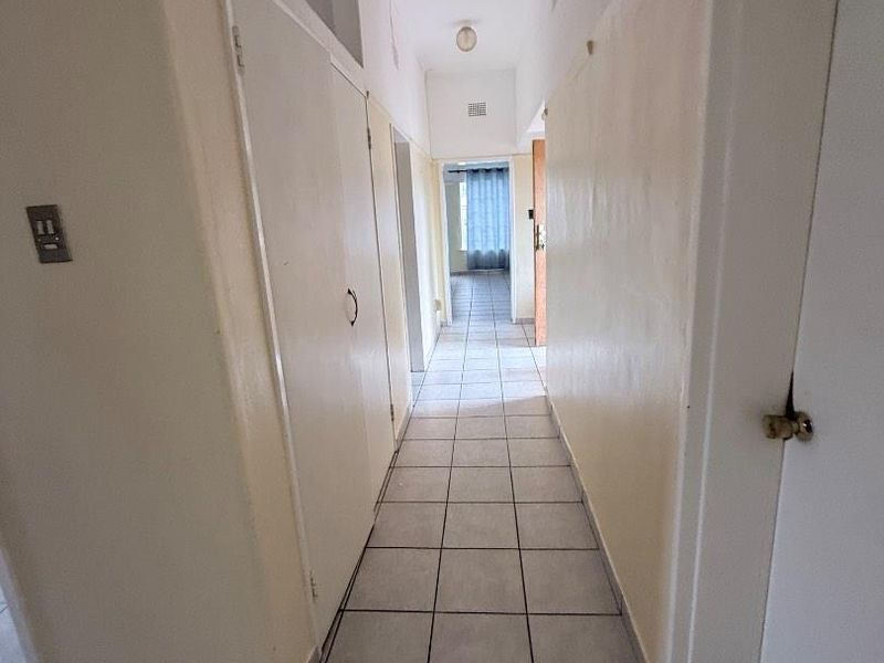 A functional hallway featuring tiled flooring and built-in storage cupboards, providing access to various rooms within the property.