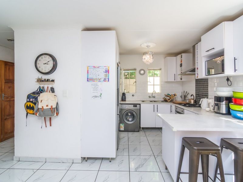 A functional kitchen featuring white cabinetry, subway tile backsplash, marble-look floor tiles, and a convenient breakfast counter for casual dining.