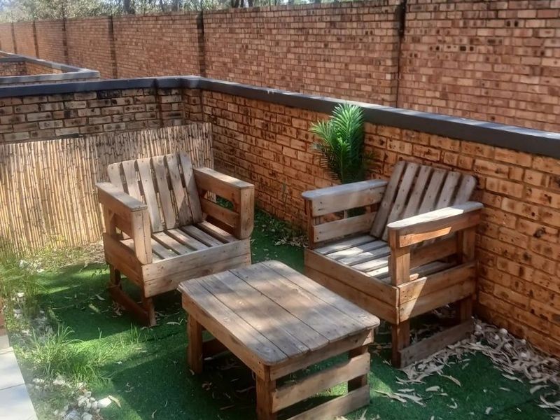 A private outdoor patio area featuring a brick boundary wall, bamboo screening, and artificial turf flooring.