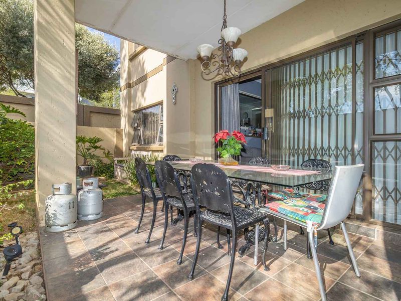 A covered patio area featuring tiled flooring, providing a seamless transition to the interior living space through sliding glass doors with security gates.