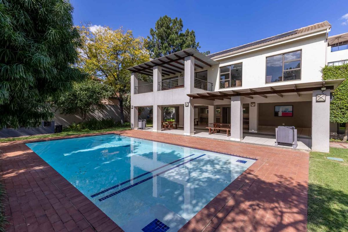 Spacious rear exterior featuring a swimming pool, brick paved surround, and a covered patio area attached to the main building structure.