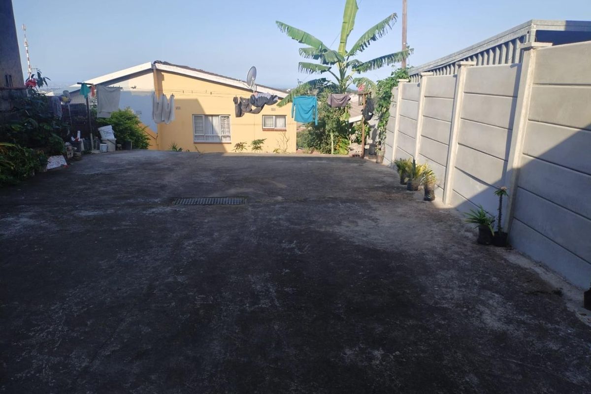A paved rear yard area featuring a precast concrete boundary wall and a central stormwater drain, offering potential for outdoor improvement.