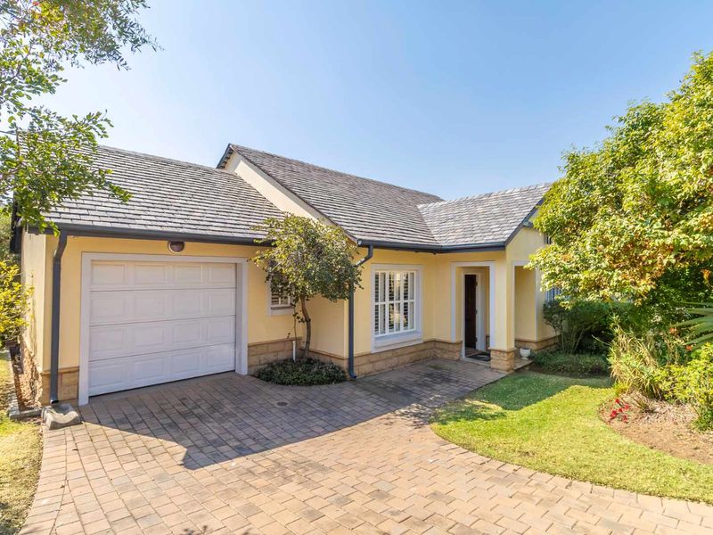 A well-maintained single-story retirement home featuring a paved driveway, single garage, stone-clad base, and a neat front garden.