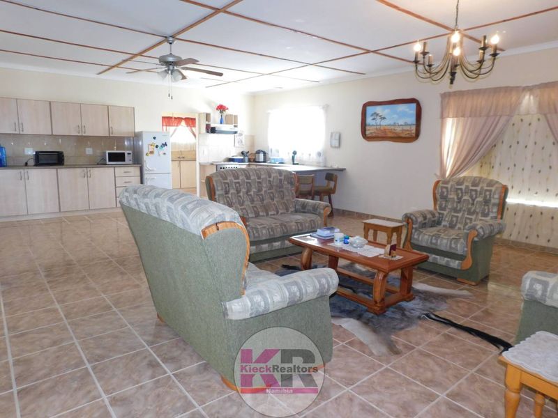 Spacious open-plan living area featuring tiled floors, a ceiling fan, and a functional kitchen with ample cabinetry and a breakfast bar.