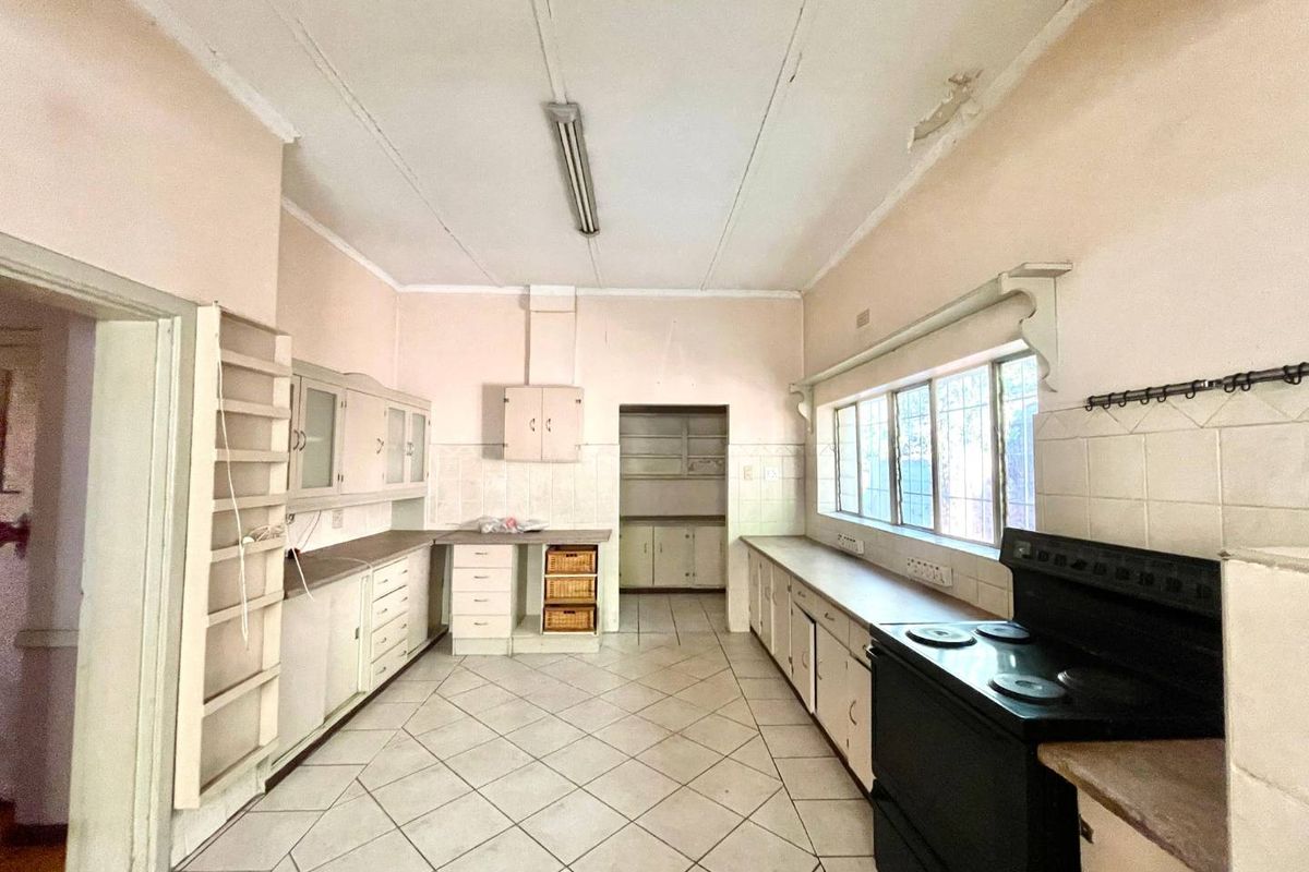 A dated kitchen featuring extensive built-in cabinetry, tiled flooring, and a tiled splashback, requiring cosmetic updates and ceiling repairs.