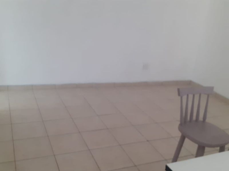 A simple, vacant living area featuring neutral tiled flooring and plain walls, offering a blank canvas for interior design.
