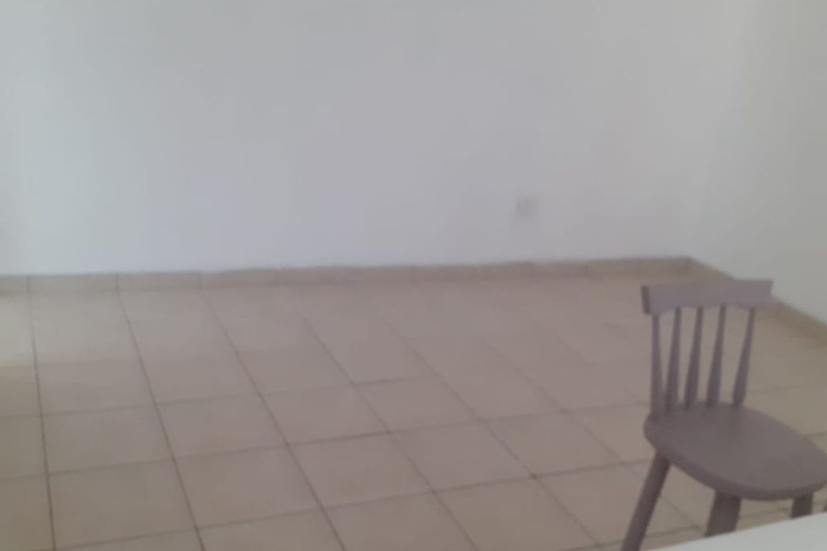 A simple, vacant living area featuring neutral tiled flooring and plain walls, offering a blank canvas for interior design.