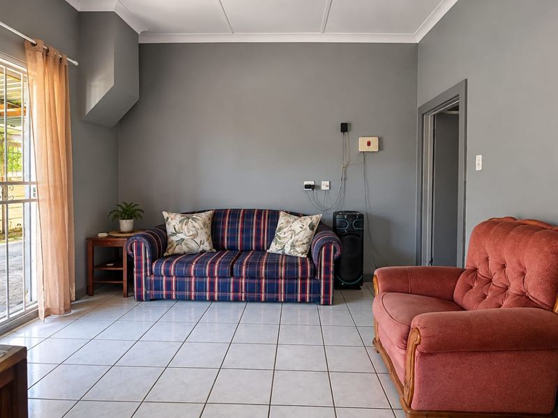 A living room featuring tiled flooring and a sliding glass door with security gate, providing direct access to the outdoor area.