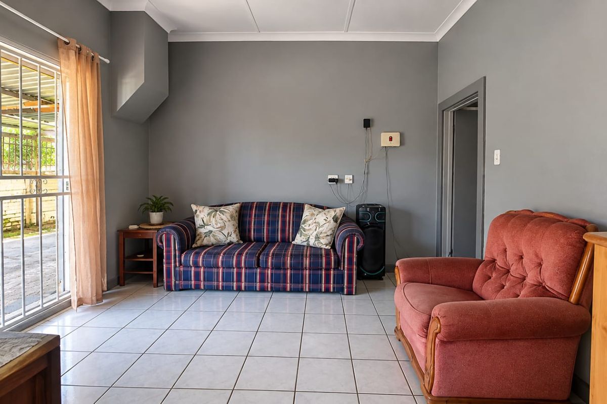 A living room featuring tiled flooring and a sliding glass door with security gate, providing direct access to the outdoor area.