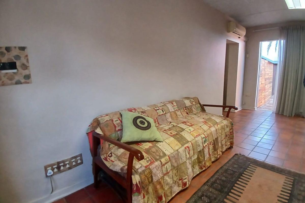 A living area featuring terracotta floor tiles, a wall-mounted air conditioning unit, and direct access to an outdoor patio space.