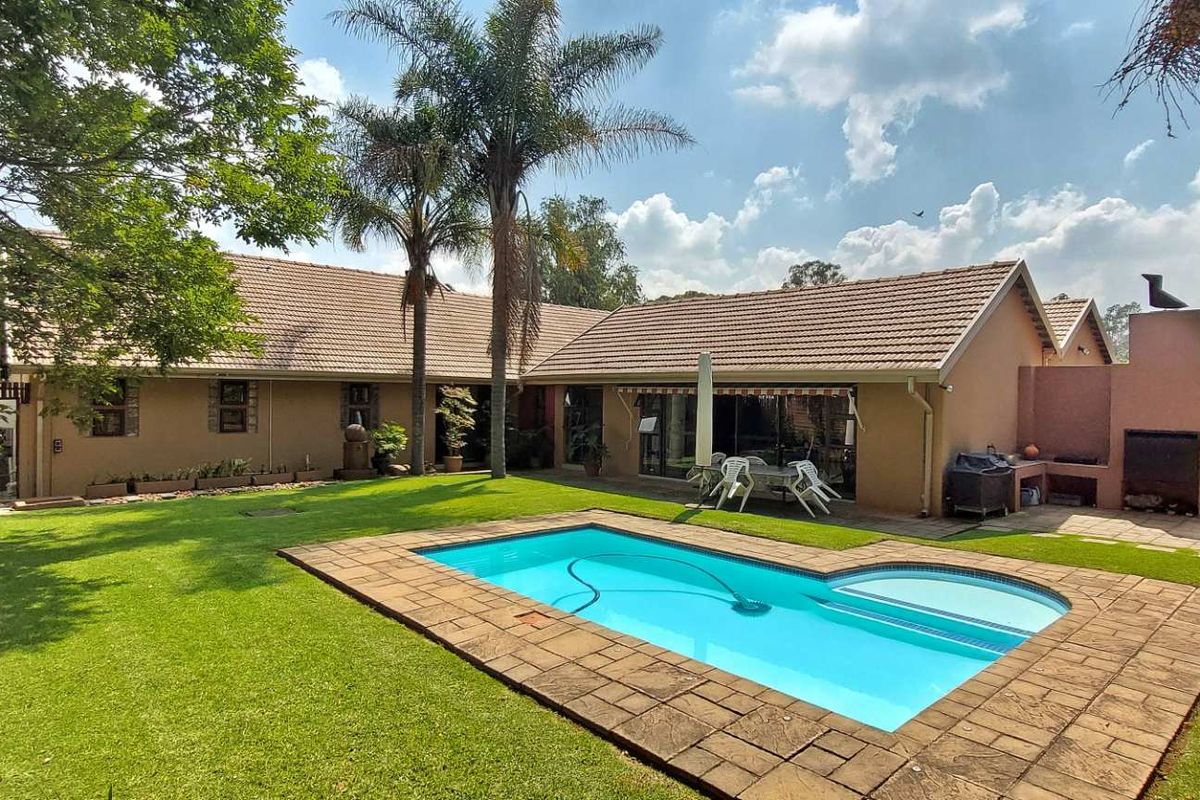 Spacious rear garden featuring a swimming pool, built-in braai area, and established landscaping, perfect for outdoor entertaining.