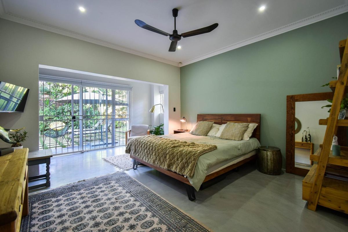 Spacious bedroom featuring polished concrete floors, a ceiling fan, and large sliding glass doors providing direct access to the rear garden.