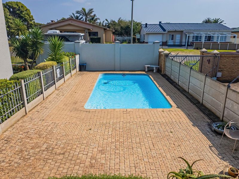 A private outdoor swimming pool area featuring a paved deck, perimeter walling, and metal fencing, providing a functional space for outdoor recreation.