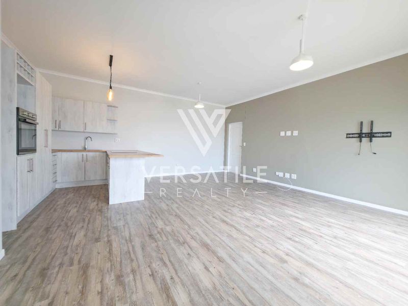 Spacious open-plan living area featuring a modern kitchen with built-in cabinetry, an island, and durable laminate flooring throughout.