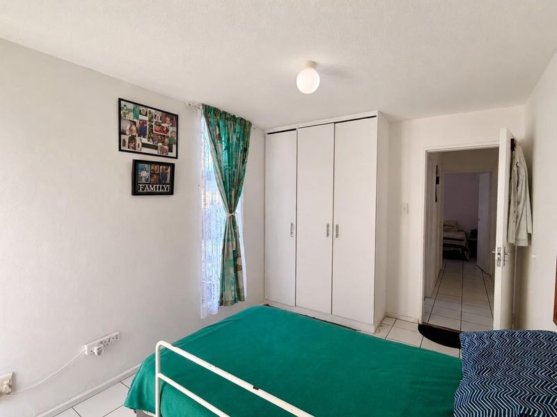 A functional bedroom featuring white built-in wardrobes and tiled flooring, providing a clean and practical living space.
