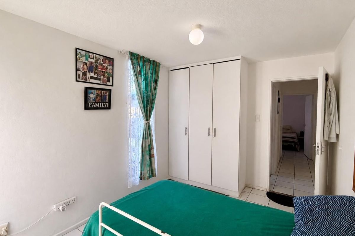 A functional bedroom featuring white built-in wardrobes and tiled flooring, providing a clean and practical living space.