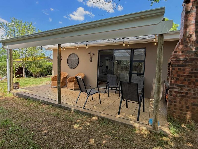 Covered outdoor patio featuring a built-in brick fireplace, tiled flooring, and direct access to the interior through sliding glass doors.