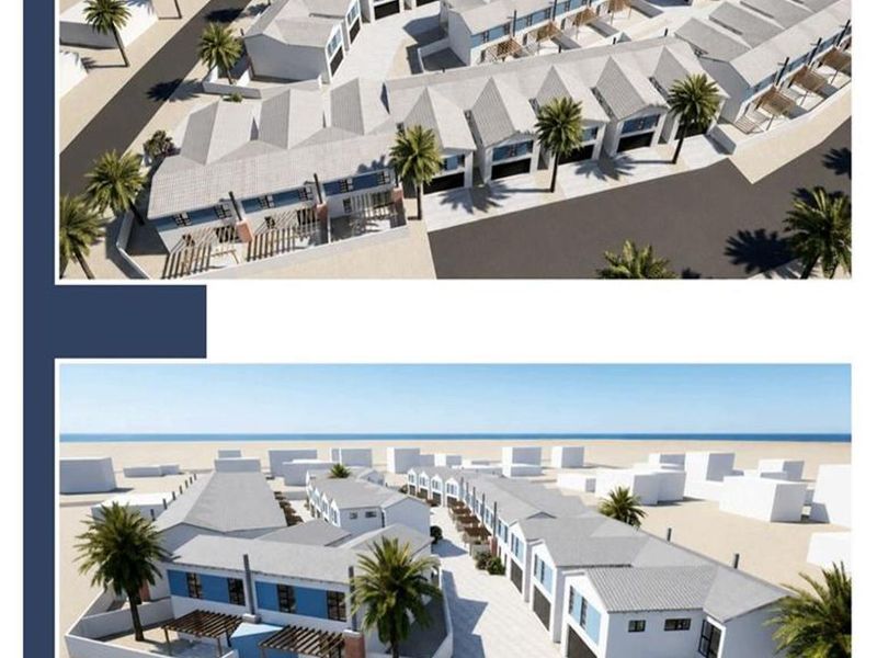 An aerial perspective of a townhouse development complex featuring multiple units, paved pathways, and landscaped grounds near the coast.