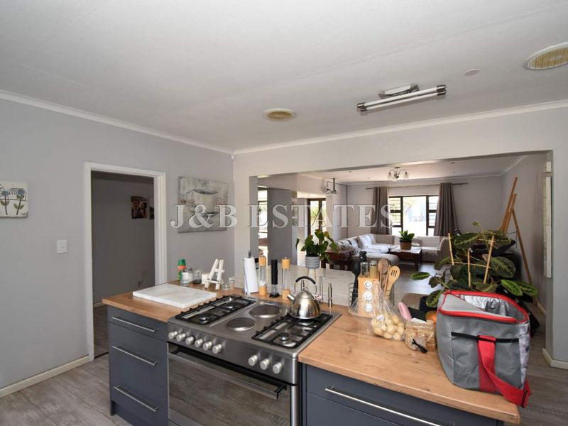 Open-plan kitchen featuring a central island with a built-in gas hob and oven, flowing seamlessly into the adjacent living area.