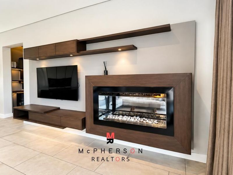 Modern living room featuring a sleek built-in fireplace, custom dark wood cabinetry, and neutral tiled flooring with integrated lighting.