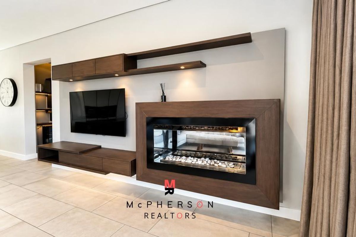 Modern living room featuring a sleek built-in fireplace, custom dark wood cabinetry, and neutral tiled flooring with integrated lighting.