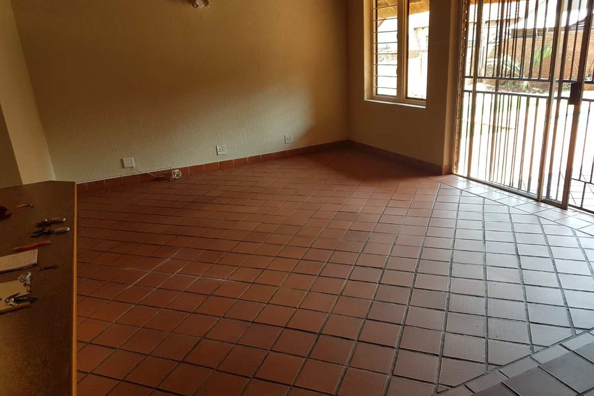 Spacious living area featuring terracotta tiled flooring, large windows for natural light, and direct access to an outdoor patio area.