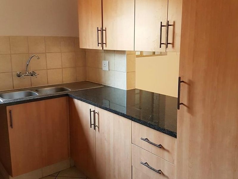 A functional kitchen featuring laminate cabinetry, granite countertops, a double bowl stainless steel sink, and tiled flooring.