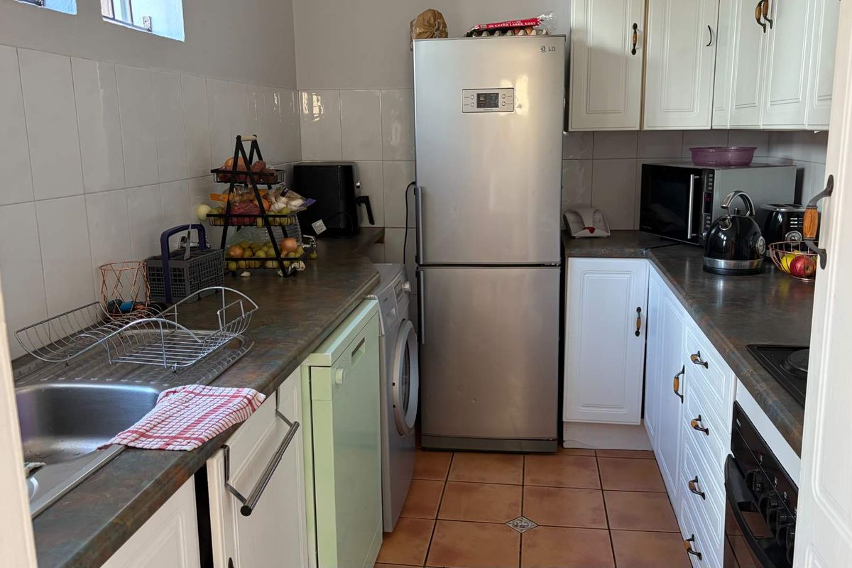 A functional kitchen featuring white cabinetry, laminate countertops, tiled backsplash, and integrated appliances, offering a practical layout for daily meal preparation.