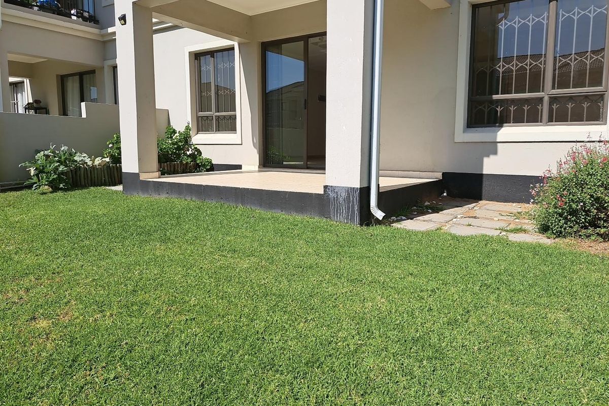 Rear view of the apartment featuring a covered patio with tiled flooring, sliding door access, and a private garden area.