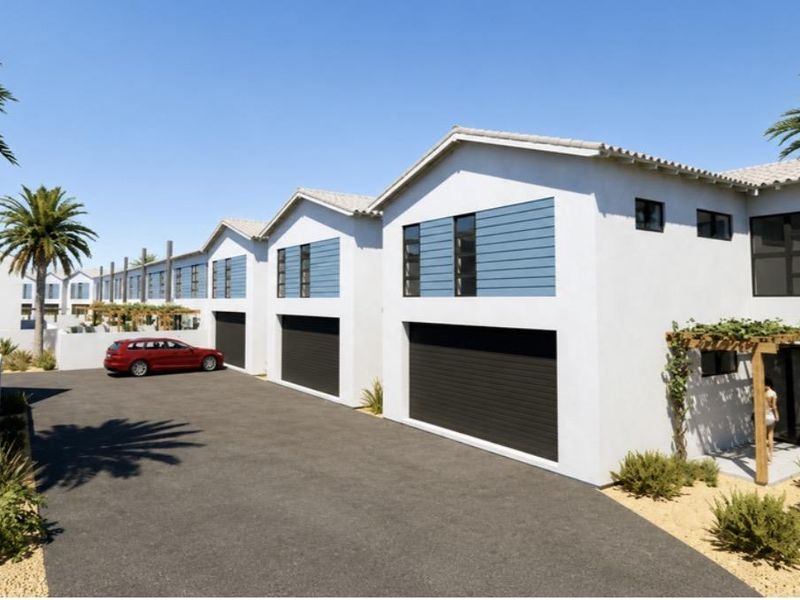 A modern townhouse complex featuring a paved driveway, multiple garage access points, and timber pergola detailing on the front facade.