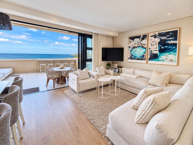Bright open-plan living area featuring seamless indoor-outdoor flow to a balcony with expansive ocean views, modern finishes, and recessed lighting.