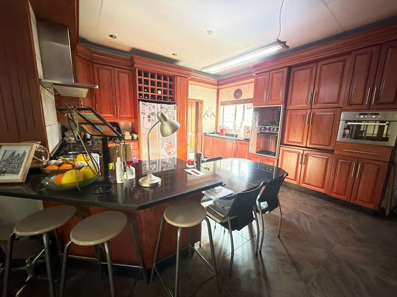 Spacious kitchen featuring extensive wooden cabinetry, granite countertops, built-in appliances, and a central island with breakfast bar seating.