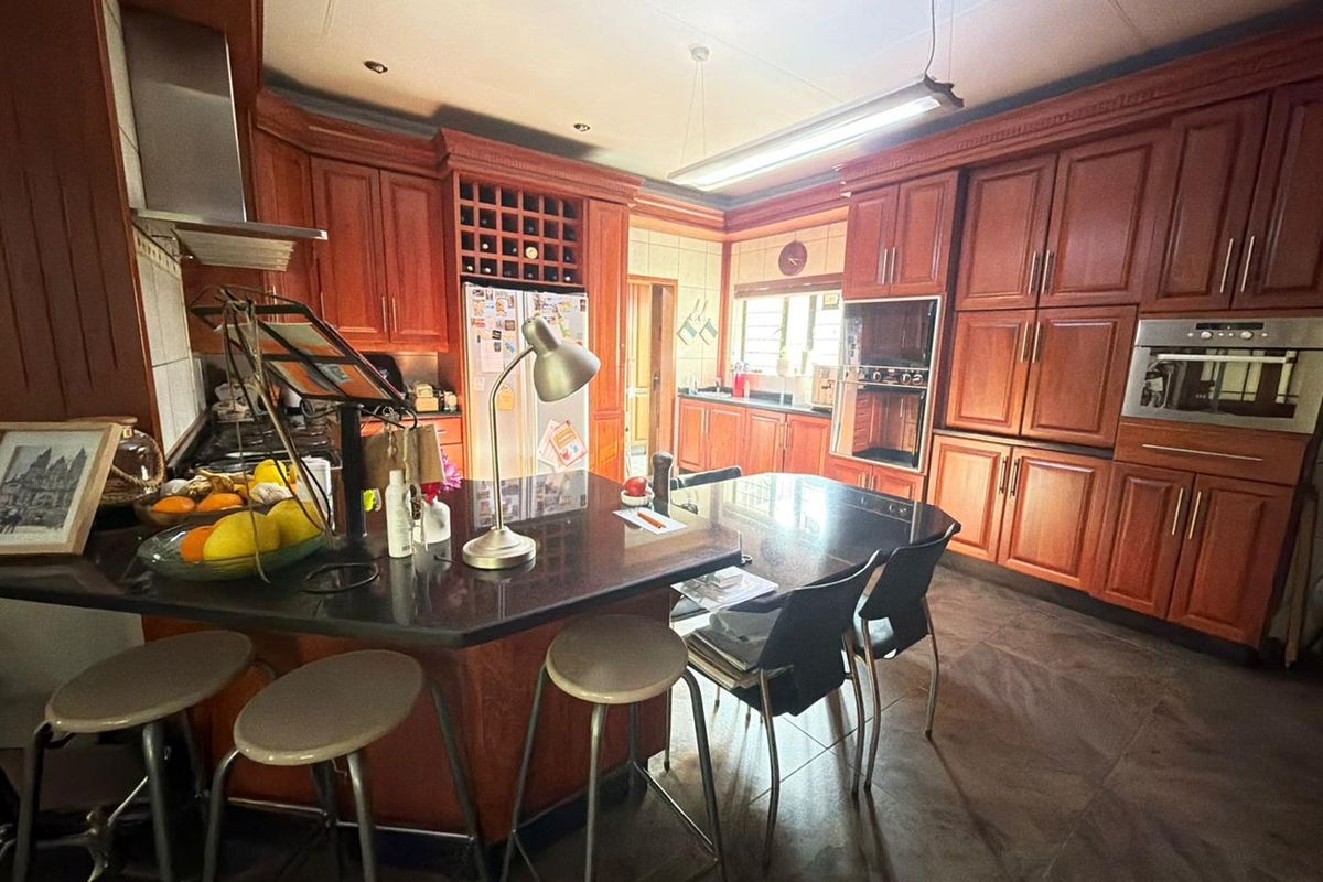 Spacious kitchen featuring extensive wooden cabinetry, granite countertops, built-in appliances, and a central island with breakfast bar seating.