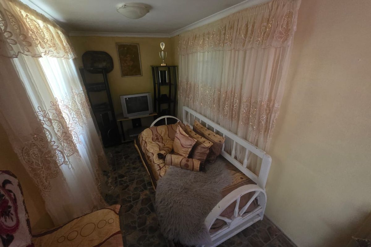 A compact bedroom featuring tiled flooring and dual window treatments, offering a functional space with potential for modernization.