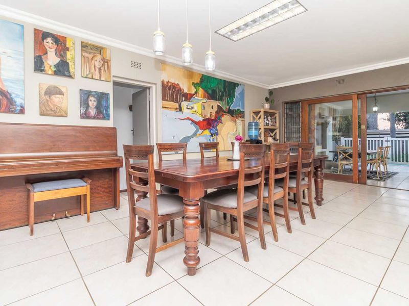 Spacious dining room featuring tiled flooring, pendant lighting, and large sliding glass doors providing access to the outdoor patio area.