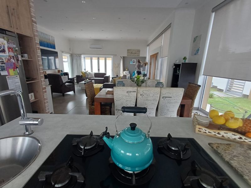 Spacious open-plan living area featuring a modern kitchen with gas hob, stone countertops, and seamless flow to the dining and lounge spaces.