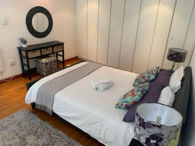 A well-maintained bedroom featuring hardwood flooring and extensive floor-to-ceiling built-in cupboards for ample storage.