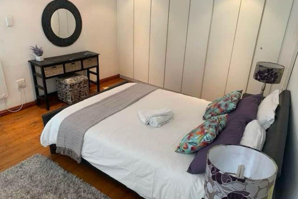 A well-maintained bedroom featuring hardwood flooring and extensive floor-to-ceiling built-in cupboards for ample storage.