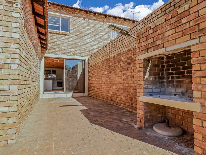 Private paved patio area featuring a built-in brick braai and direct access to the interior through a sliding glass door.