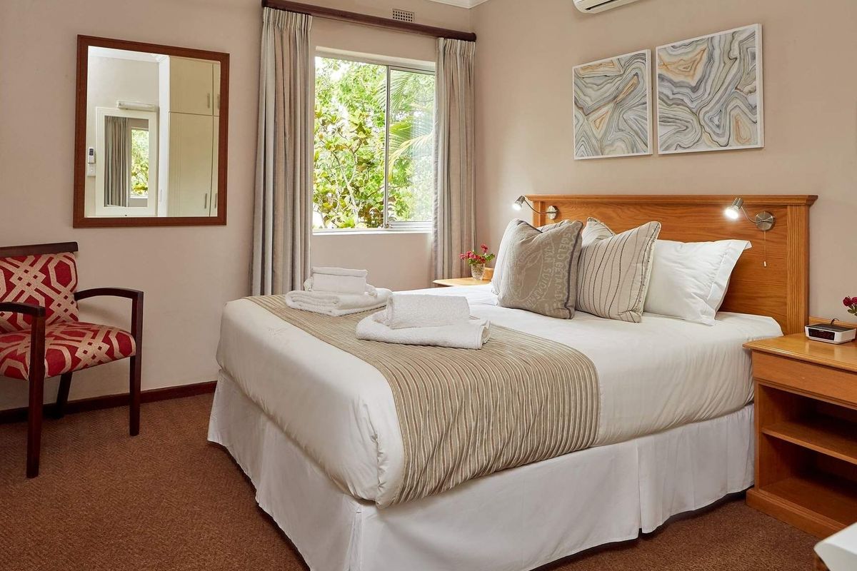 A well-maintained bedroom featuring carpeted flooring, a wall-mounted air conditioning unit, and a window with natural light.
