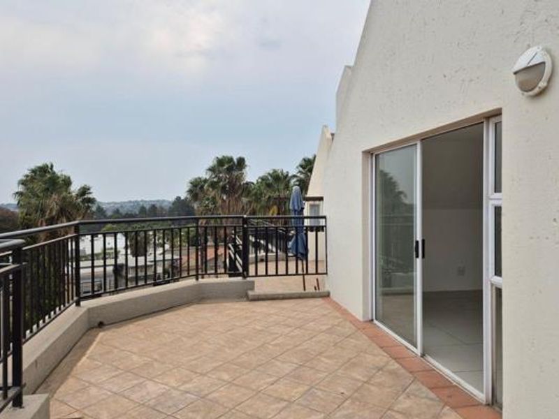 A spacious tiled balcony featuring metal railings and a sliding glass door, offering an elevated outdoor area with scenic views.