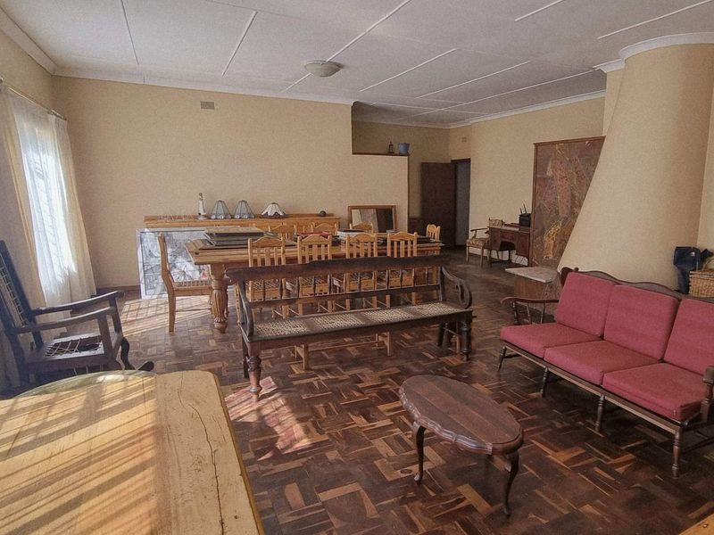 Spacious open-plan living and dining area featuring traditional parquet flooring and a prominent built-in fireplace, offering a versatile layout for family living.